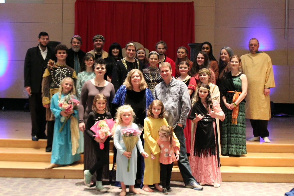 A group of children and adults in costumes posing indoors.